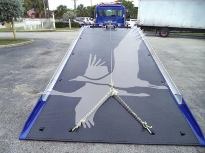 Kenworth T280 rollback truck bed with a raised hydraulic platform, blue frame, and chains securing the surface.