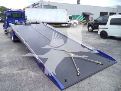 Kenworth T280 rollback truck bed with lowered ramp and chains, blue exterior, in a parking lot with other vehicles.