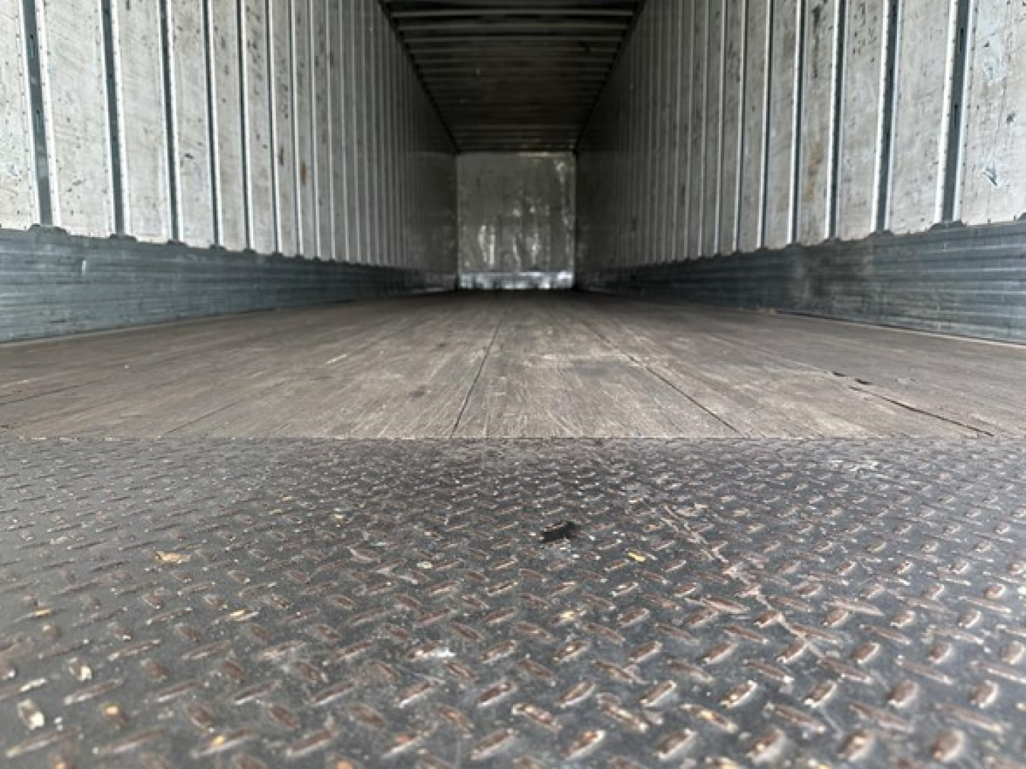 Truck trailer interior with diamond plate floor and metal side walls, empty cargo area.