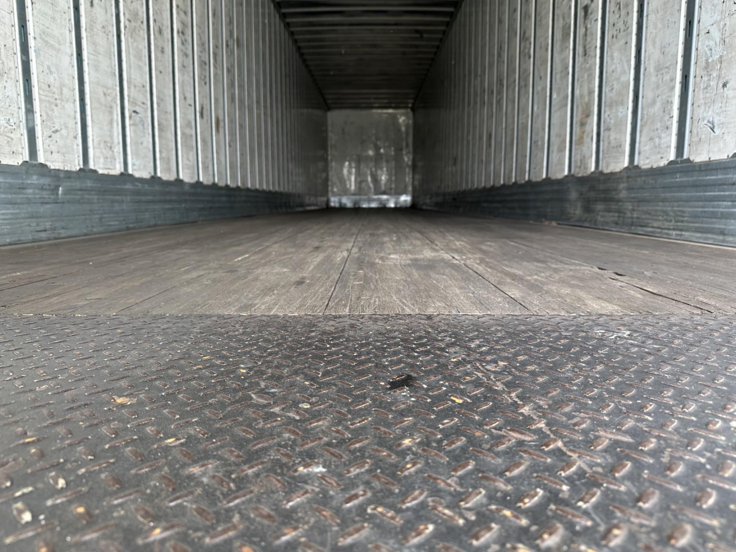 Interior of trailer or cargo space showing metal sidewalls and diamond plate floor from front view; empty cargo area.