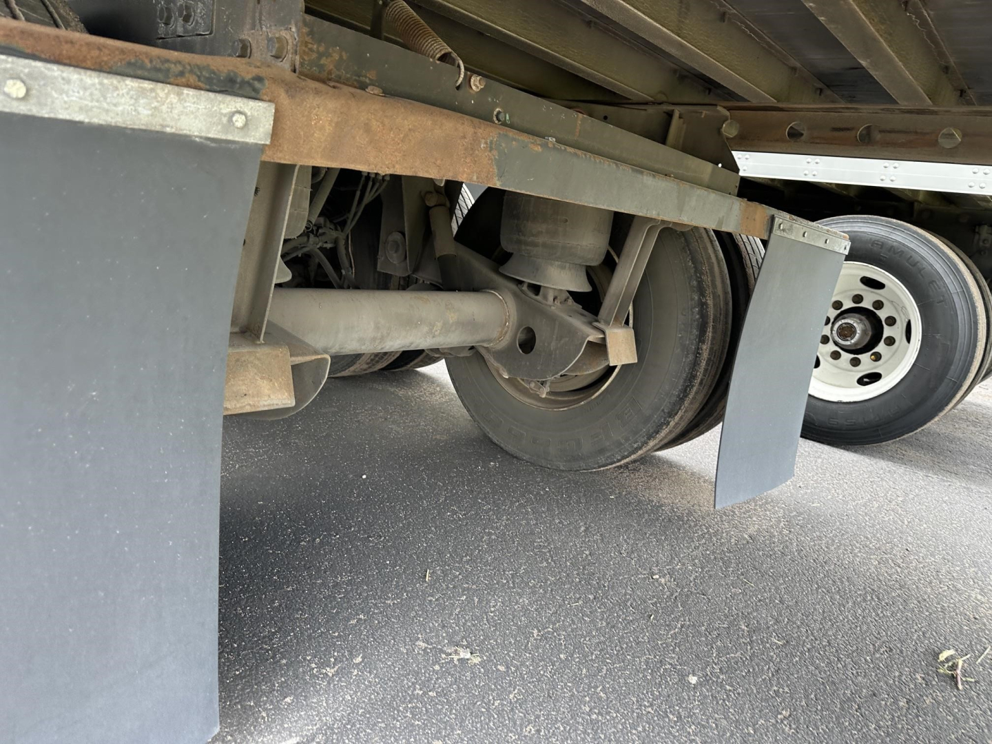 Trailer undercarriage showing axle, suspension, and wheel assembly of a 2016 Utility 4000DX trailer with mud flaps and metal frame.