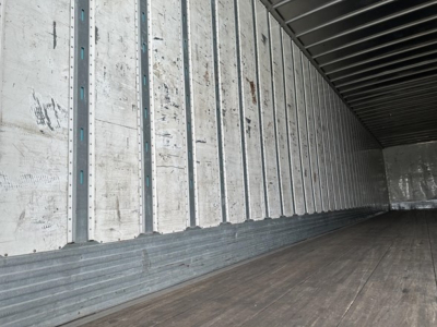 Trailer interior showing wooden floor and metal side walls with vertical rails; empty cargo space.
