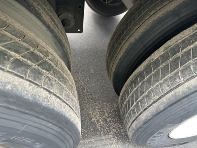 Two trailer tires with tread and dirt on the ground between them. No additional readable text visible.