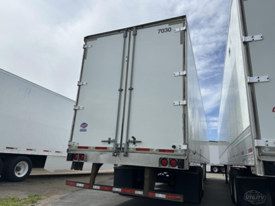 Rear view of a Utility 4000Dx trailer showing closed double doors, rear lights, and bumper with a stock number 7030 label; side trailer wheels visible.