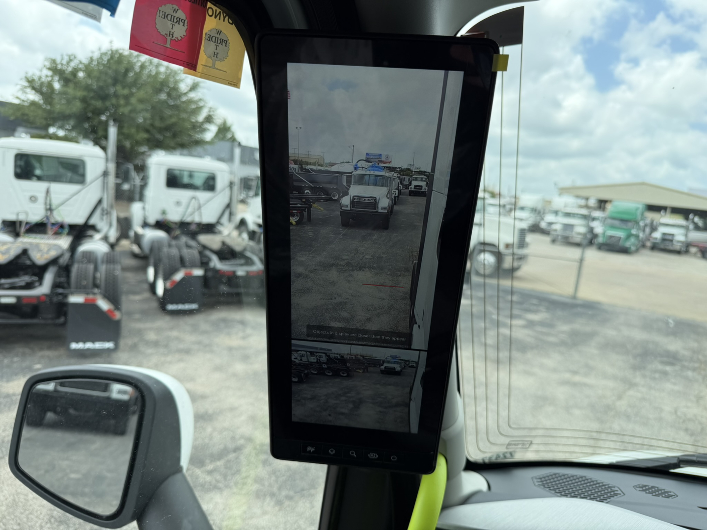 Volvo VNL64T860 truck in showroom showing a vertical tablet display inside cab with other trucks in background.