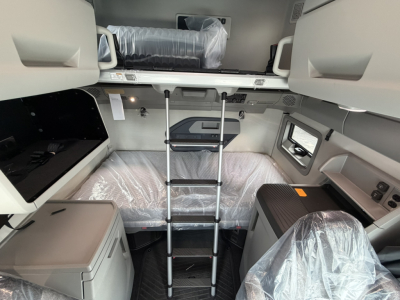 Volvo VNL64T860 cab interior view with upper bunk, ladder, and storage cabinets; plastic-wrapped seats and panels visible.