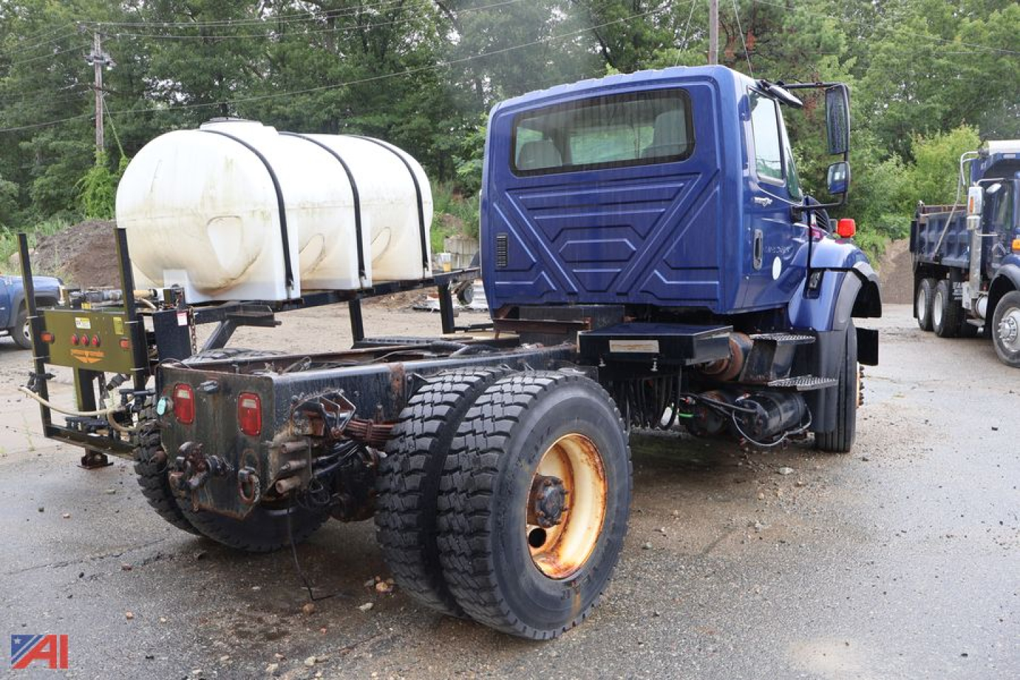 Cab and chassis of a 2011 International WorkSTAR 7400 showing blue cab, rear dual tires, white spare tank, and hitch area.