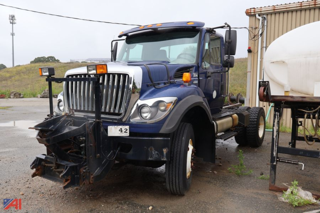 Cab and chassis truck in blue with front plow attachment, International WorkStar 7400, visible grille, headlights, and dual rear wheels.