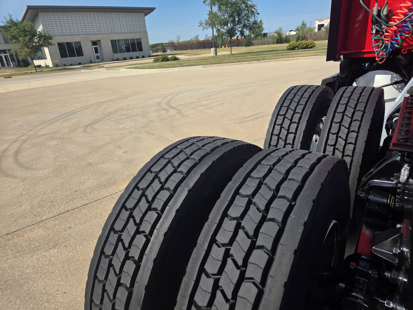 Kenworth T680 truck chassis showing dual rear axles with tires and suspension components in an outdoor lot.