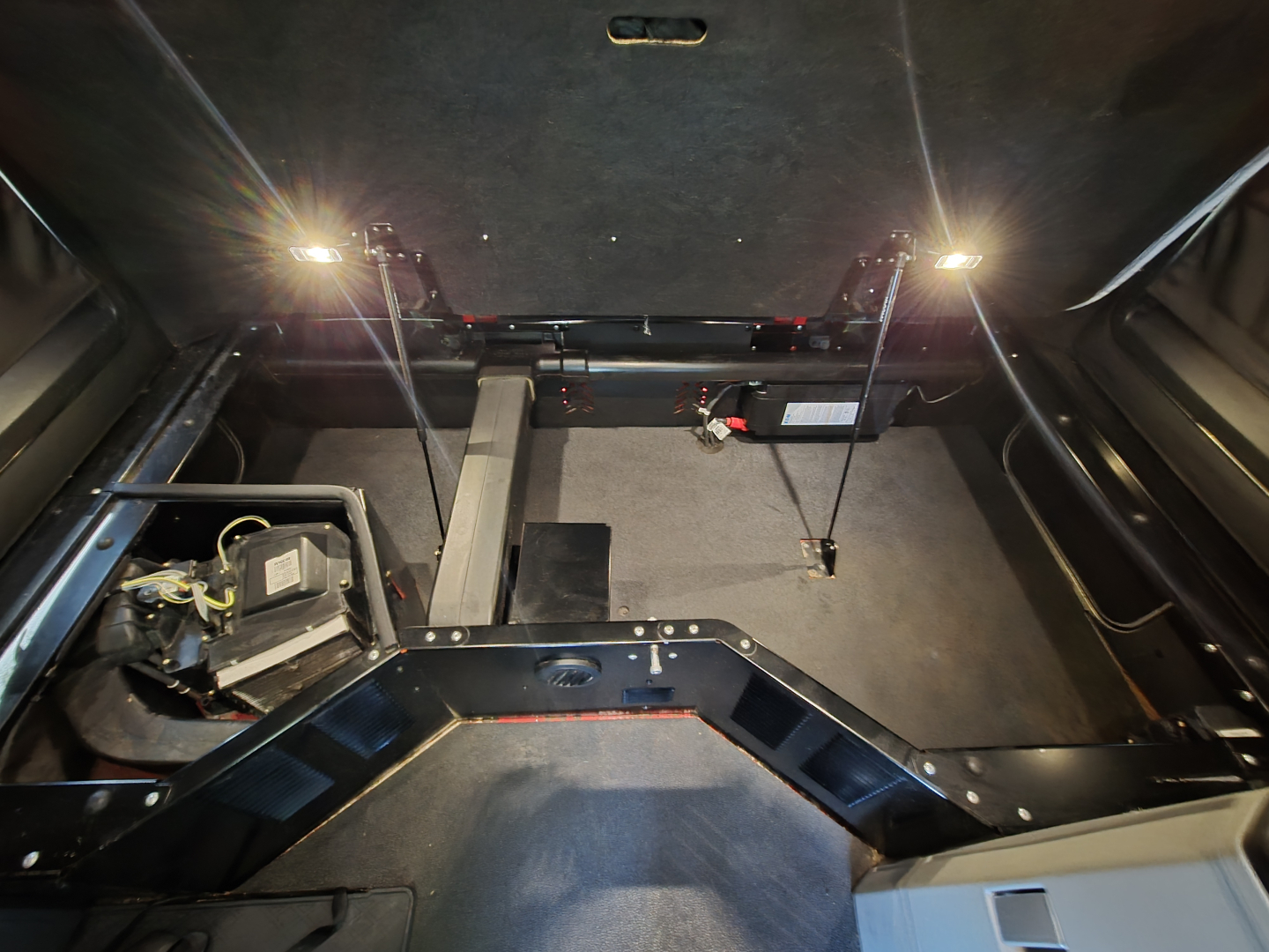 Kenworth T680 interior floor area with sleeper cab and wiring, showing under-seat storage and mounted components.