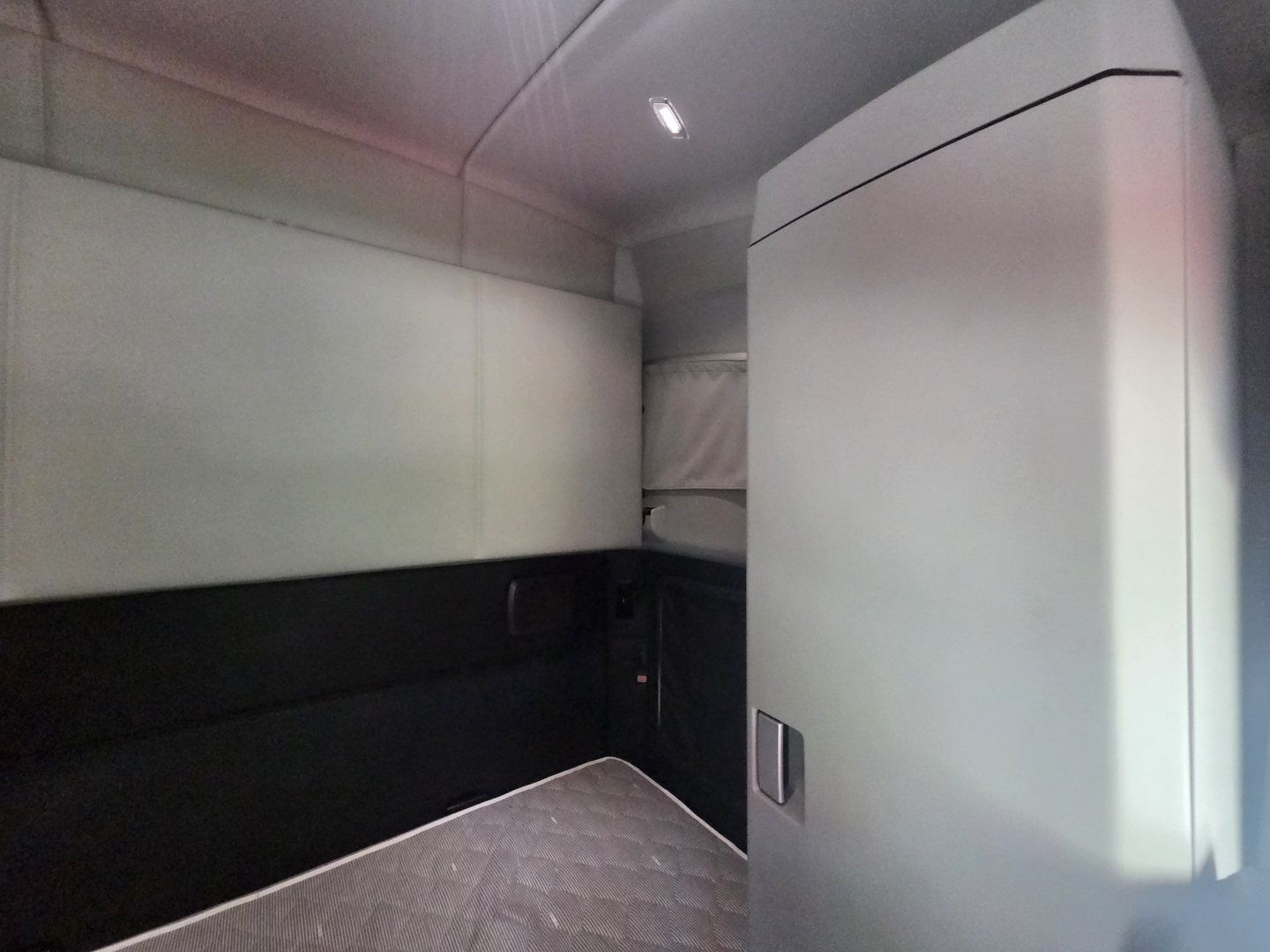 Kenworth T680 sleeper cab interior showing side walls, upper bunk area, and a tall storage cabinet.
