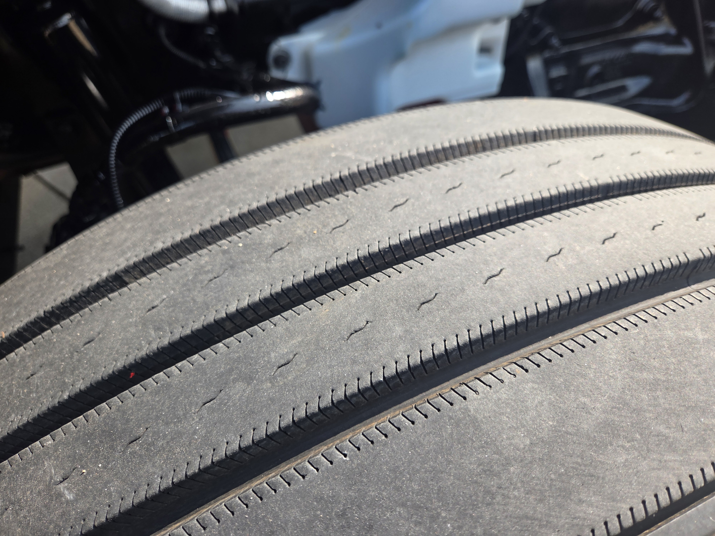 Tire tread close-up on a Kenworth T680 sleeper tractor showing dual rear wheel tread and part of chassis wiring