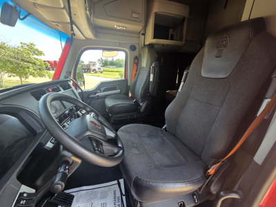 Kenworth T680 cab interior showing steering wheel, driver's seat, and dashboard with gray fabric seats.