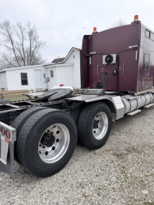 Kenworth W900L tractor rear view showing chassis and dual rear axles with tires, maroon sleeper cab, and exposed fifth wheel.