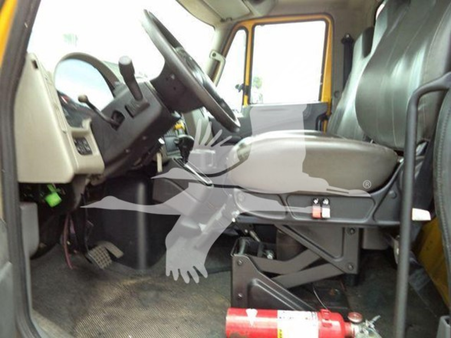 Truck cab interior of a 2019 International Durastar 4300 showing steering wheel and driver seat with floor pedals and dashboard details.