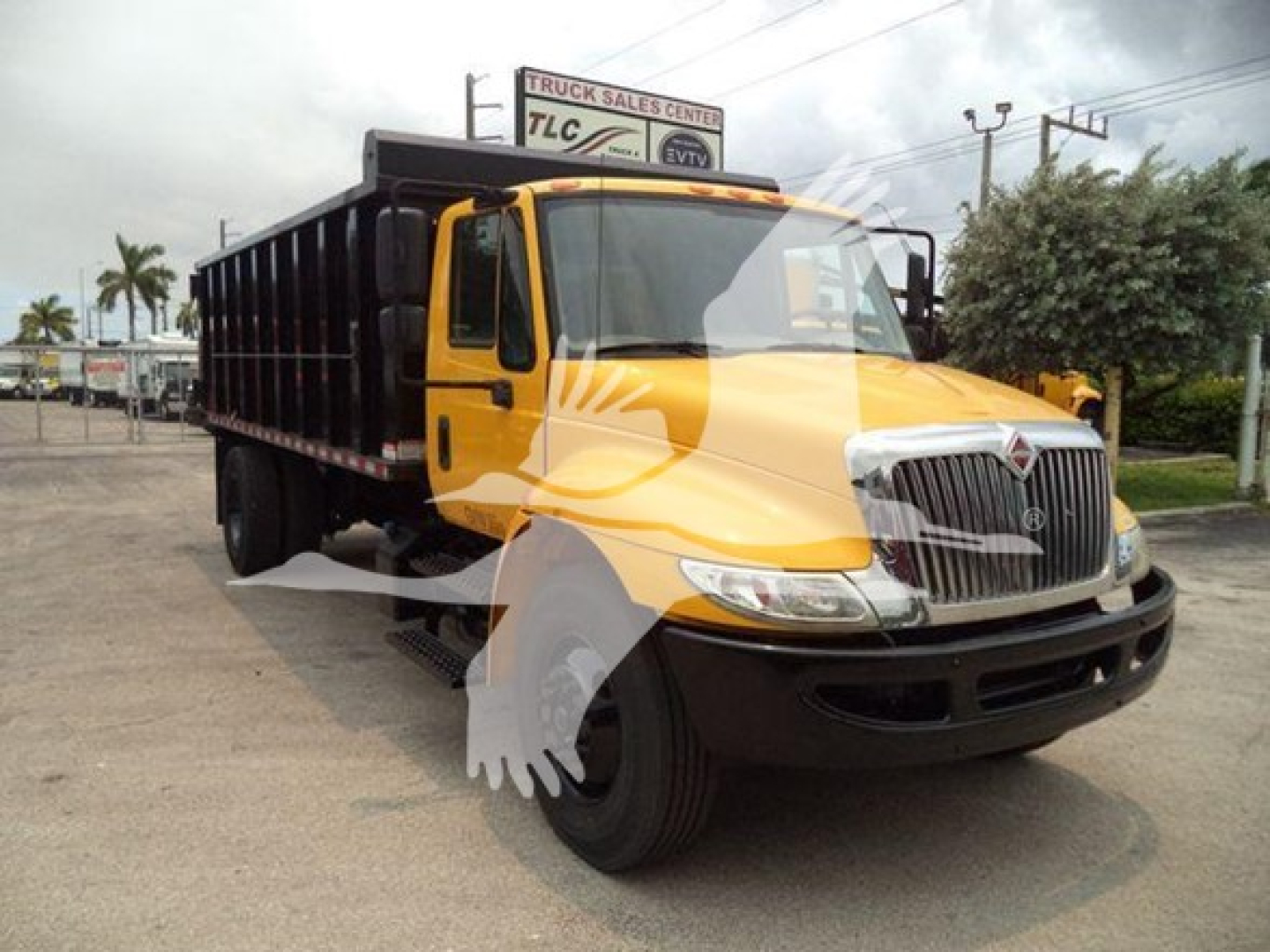 Dump truck 2019 International Durastar 4300 with yellow cab and black dump bed, front grille chrome, side view mirrors, in-service label visible near windshield.