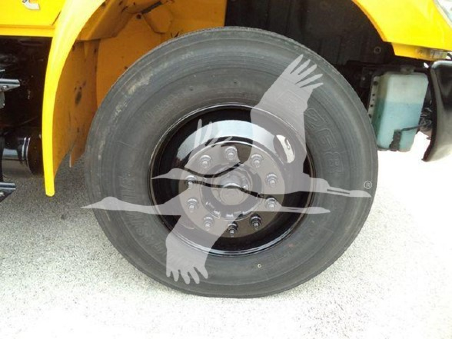 Wheel and tire close-up on a yellow 2019 International Durastar 4300 dump truck front fender area showing front axle.