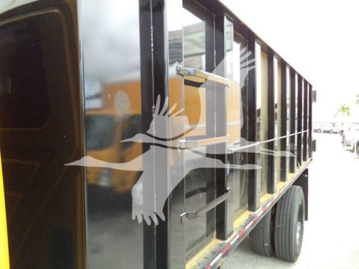 Dump truck side view showing black dump body and wheels.