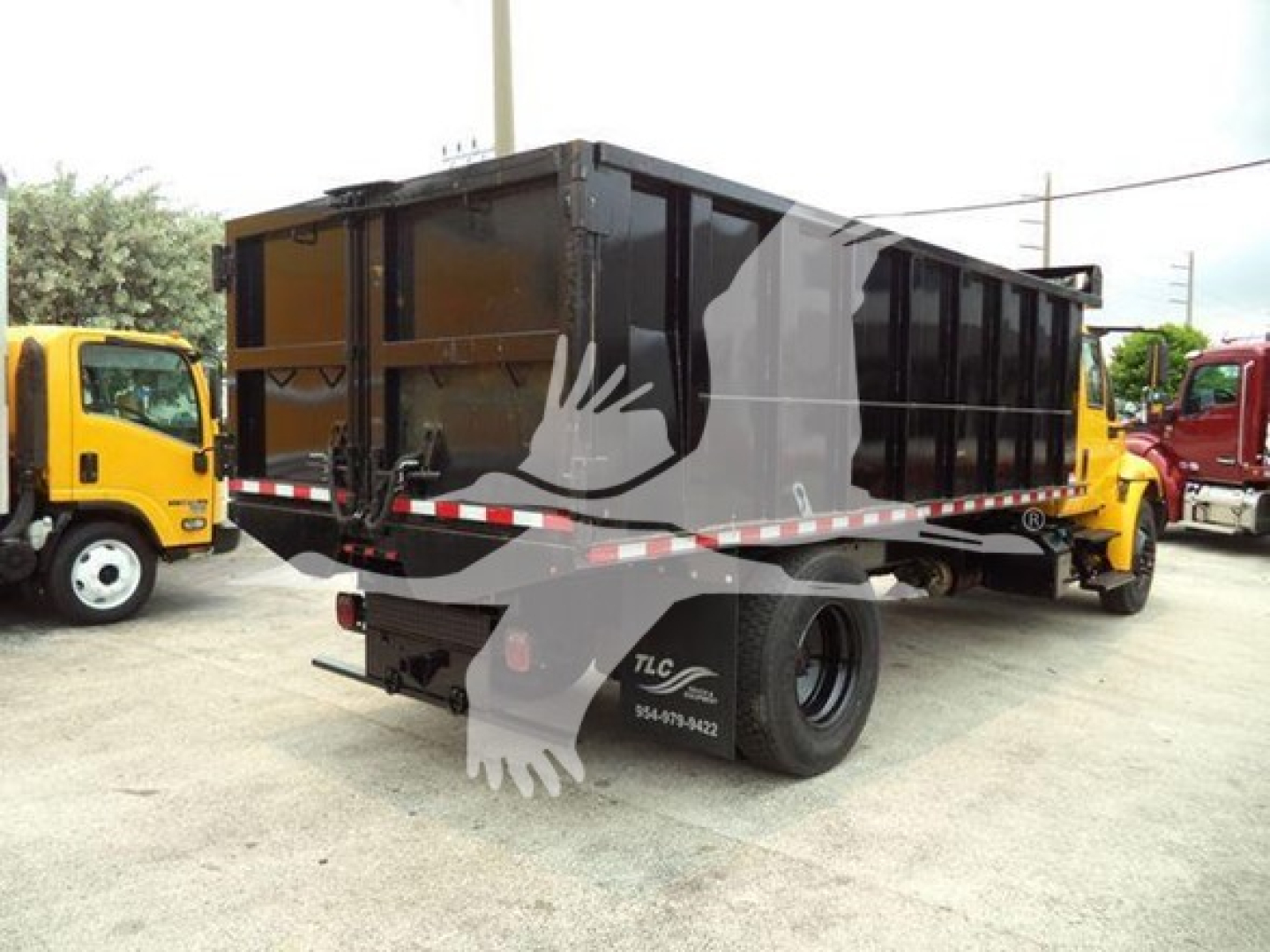 Dump truck dump bed with black body and yellow cab seen from rear-side angle.