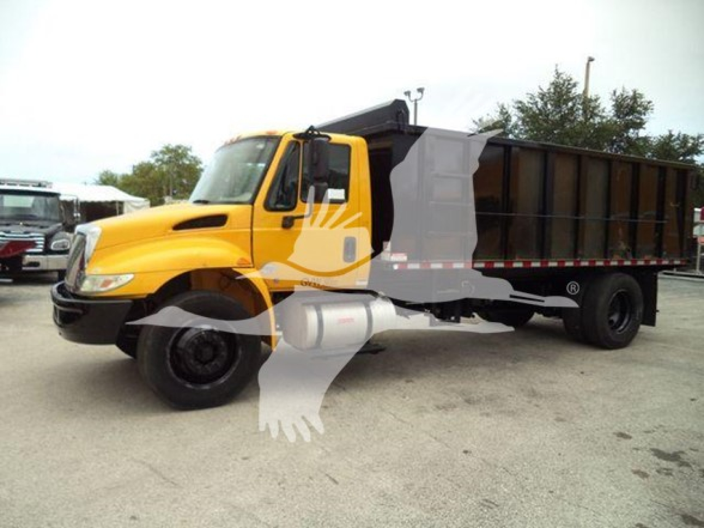 Dump truck showing a yellow International Durastar 4300 cab with a black dump bed, side view, stock number T83586, VIN partially visible, in a parking lot.