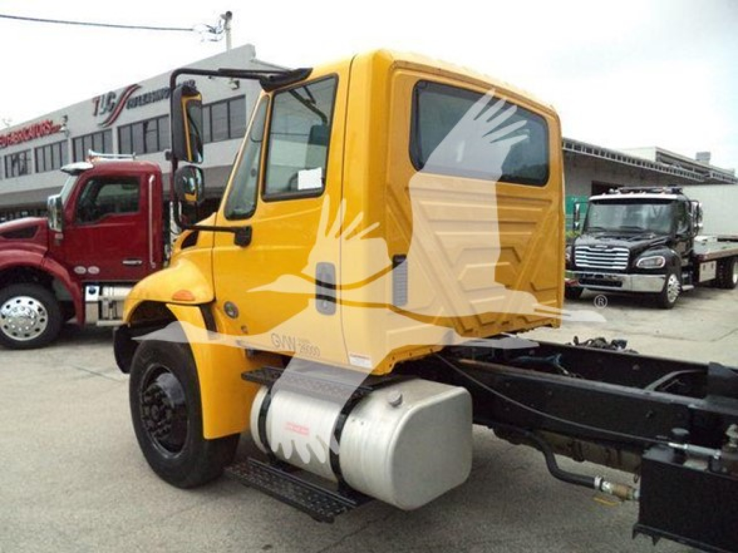 1970s-2019 International Durastar 4300 dump truck cab in yellow with side fuel tank, chassis exposed at rear, front wheel view.