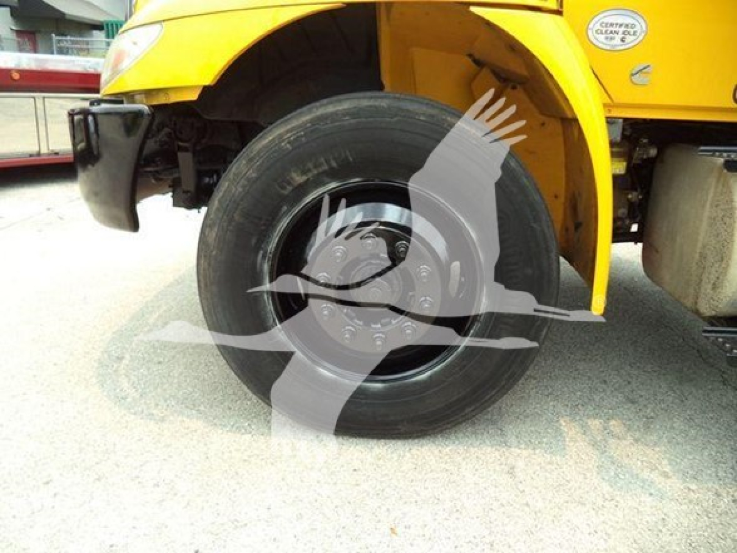 Dump truck wheel area showing front left tire and hub with tire mounted under a yellow International Durastar 4300 cab.