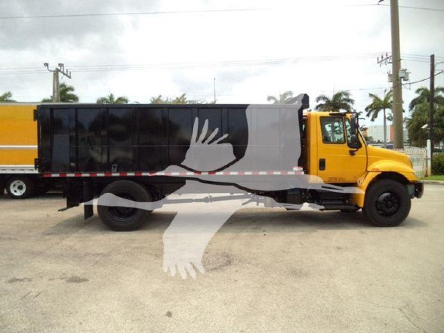 Truck side view with yellow cab and black/gray dump body. Visible text on image includes no specific legible labels or stickers beyond generic truck silhouette overlaid by a white scratch-like watermark.