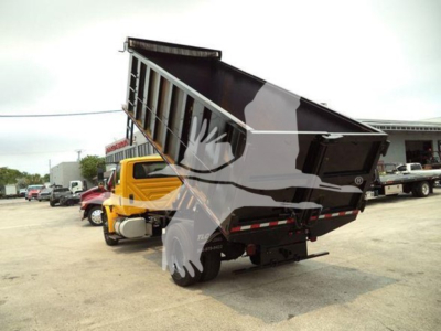 Dump truck in yard with raised dump bed and yellow cab, International 4300 model.