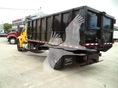 Dump truck with black dump body attached to a yellow International Durastar 4300 cab, side and rear view showing hydraulic tailgate.