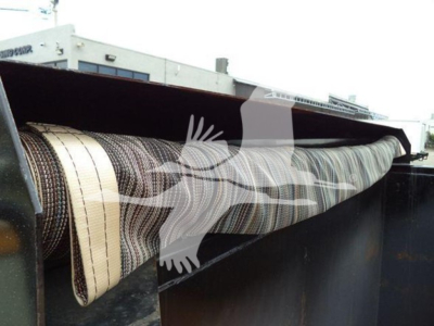 Dump truck bed with rolled conveyor belt/mesh material visible inside cargo area.