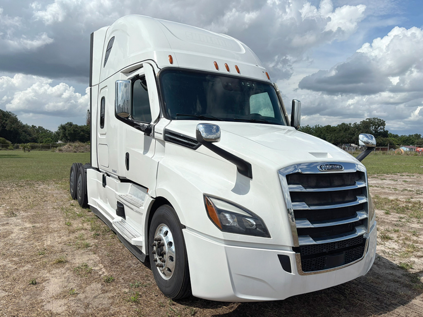 Freightliner Cascadia126 truck front driver's side view showing chrome grille, headlights, and white tractor with aerodynamic mirrors.