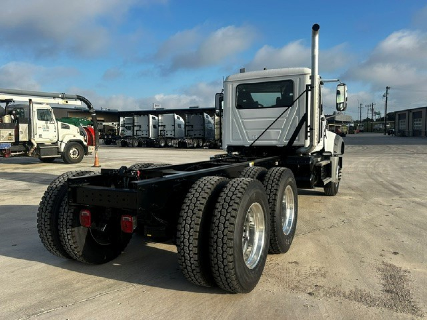 Mack GR64F chassis in driveway showing rear dual axle and cab with vertical exhaust. VIN 1M2GR4GC3VM058689 not visible on image, but truck frame and tires visible.