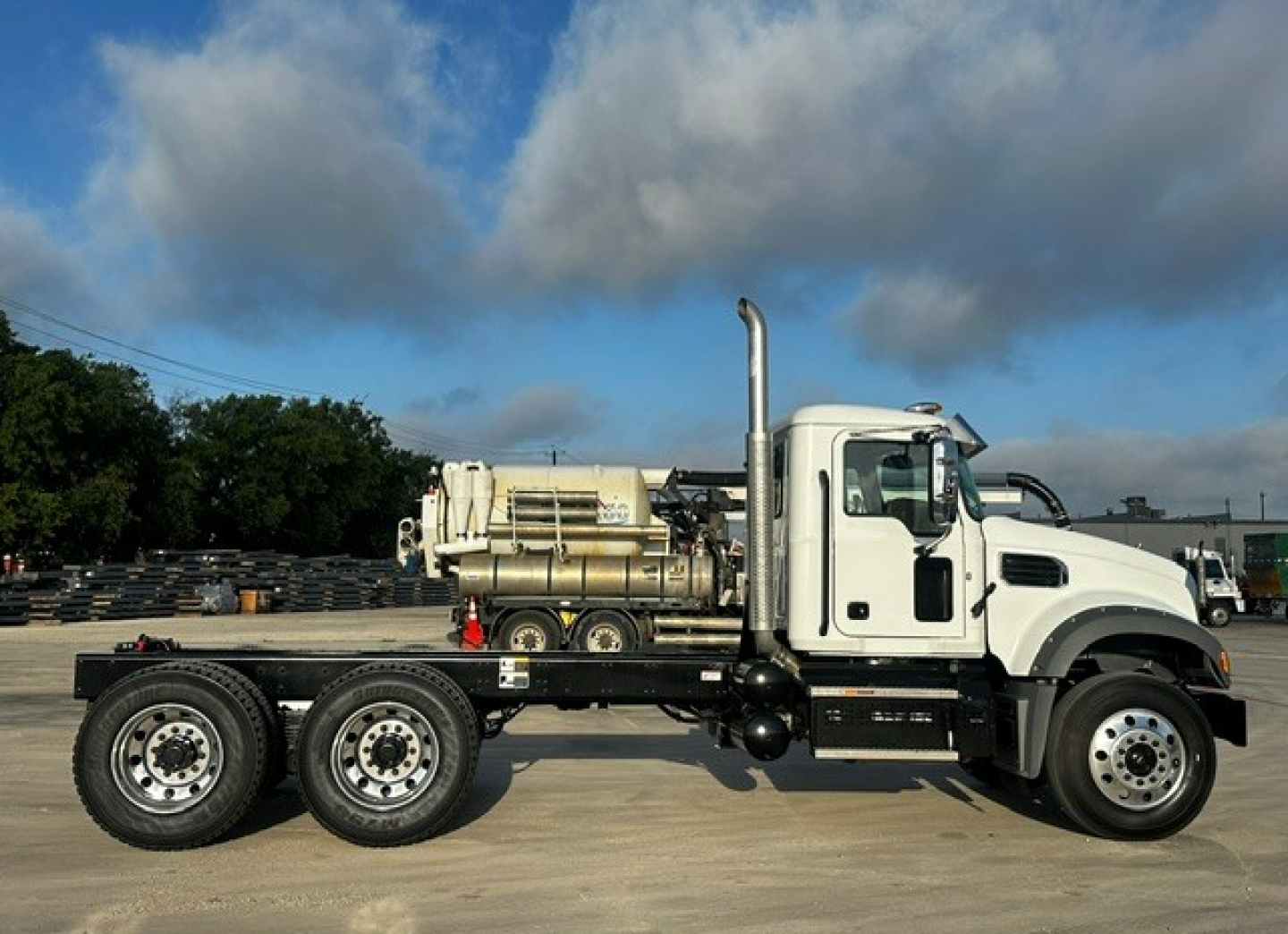 Mack GR64F dump truck side view showing chassis, rear dual axles, and integrated diesel tank with large exhaust stack.