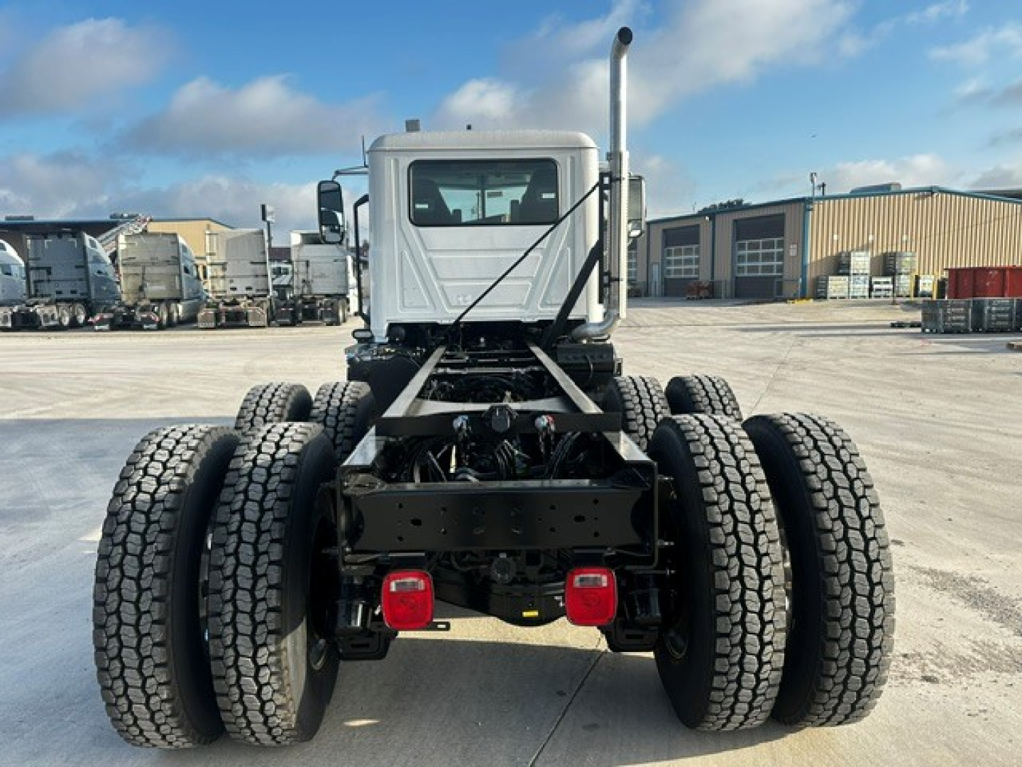 Truck rear view of a 2027 Mack GR64F dump truck showing dual rear axles with dual tires and chassis frame; visible exhaust stack and rear lights.