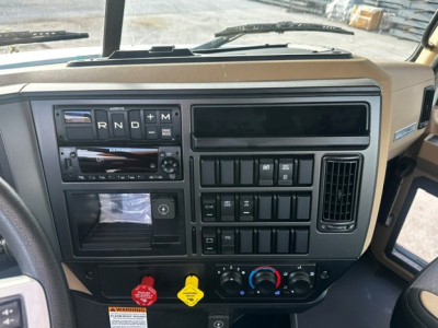 Mack GR64F cab dash view showing steering area and control panel with R N D + M gear positions, climate controls, and switches.
