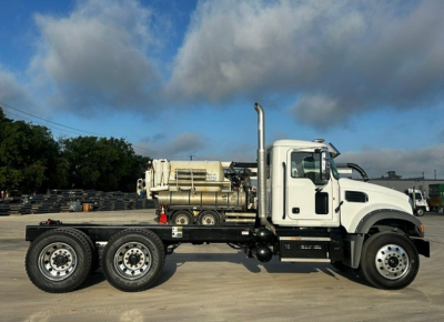 Mack GR64F dump truck side view showing chassis, rear dual axles, and integrated diesel tank with large exhaust stack.
