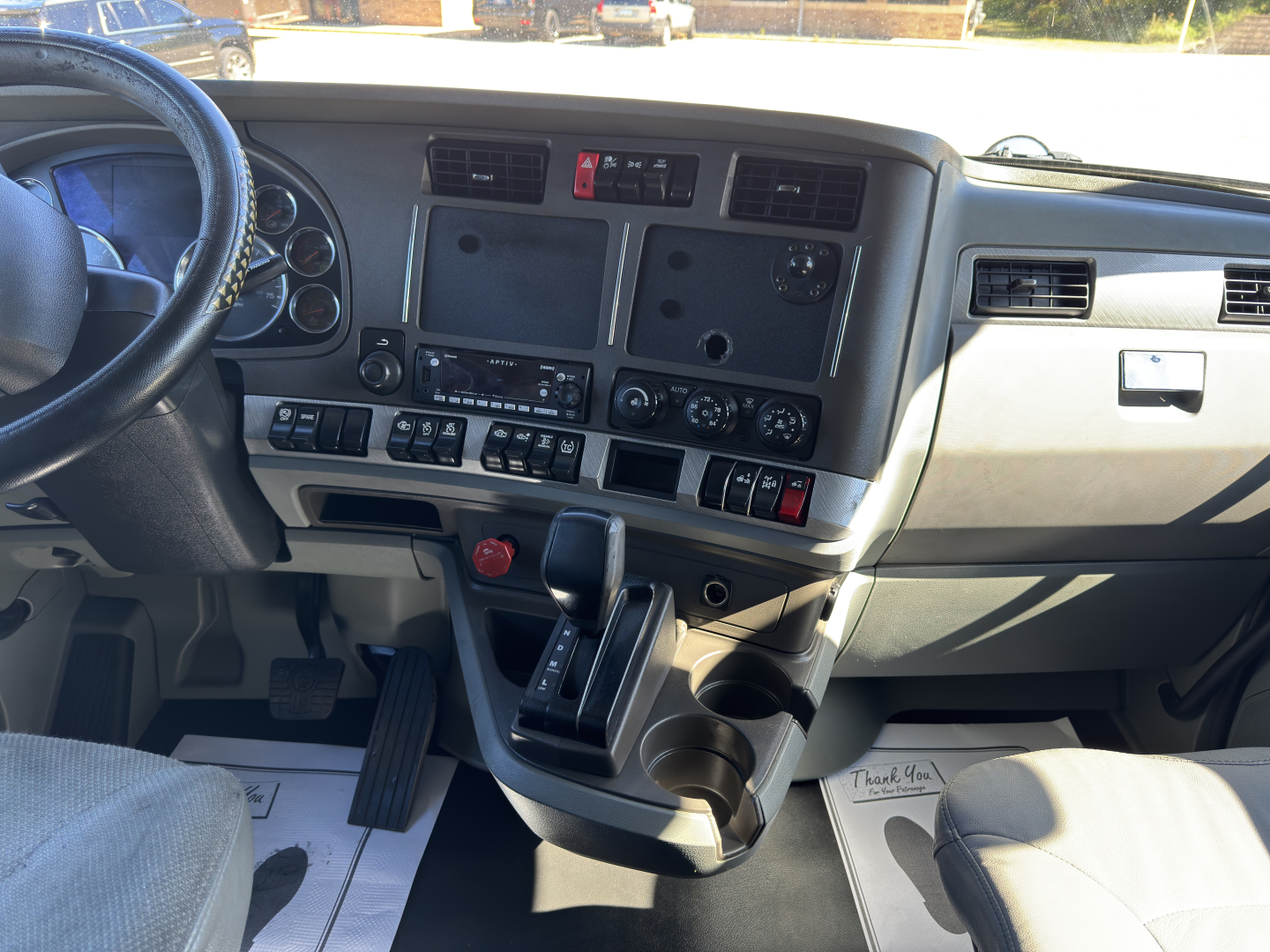 Kenworth T680 truck interior dashboard center console with multiple screens and controls.