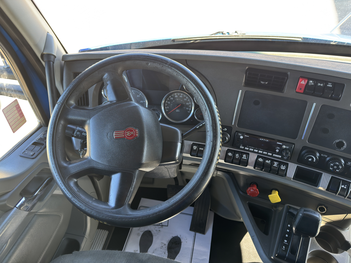 Kenworth T680 interior showing steering wheel dashboard and controls with digital display.