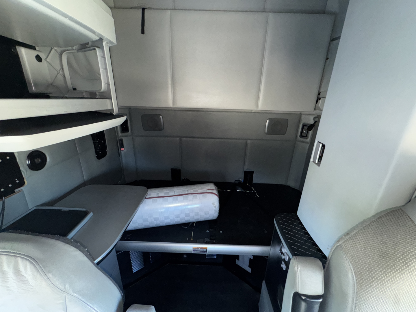 Truck sleeper cab interior of a 2015 Kenworth T680 showing a bunk bed area and storage compartments.