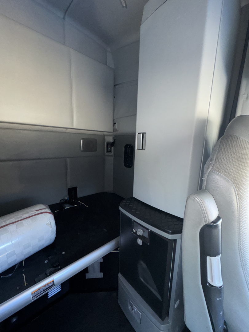 Kenworth T680 interior sleeper cab showing storage cabinet and workspace area.