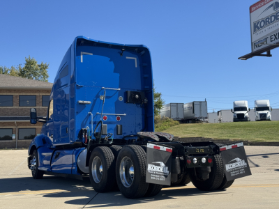 Kenworth T680 sleeper tractor rear view showing blue paint, dual rear axles, mud flaps with Kordel logos, rear lighting, and fifth-wheel area.