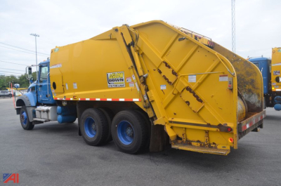Yellow refuse truck body attached to blue cab, with caution decals and rear loader; side shows 'SLOW DOWN' sign and brand stickers.