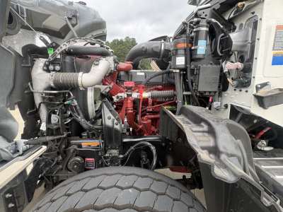 Mack GR84F dump truck engine bay with red engine block, hoses, and various labels visible.