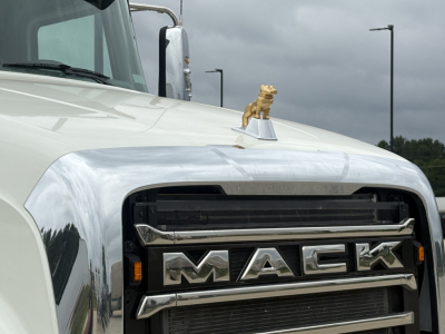 Truck hood ornament on a white Mack GR84F showing the grille and MACKA chrome emblem.