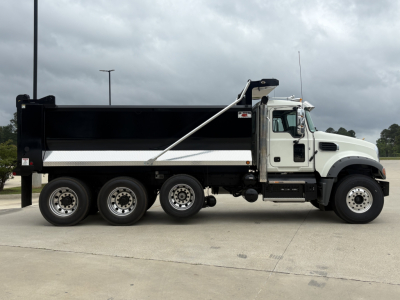 Dump truck side view showing Mack GR84F with white cab, black dump bed, and triple rear axle. Visible text includes VIN plate and stock number not legible in image.