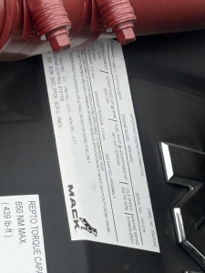 Tag showing vehicle details and specifications for a 2027 Mack GR84F dump truck, with VIN 1M2GR3NC3VM009411 and stock 72321, label text including max payload and engine info.