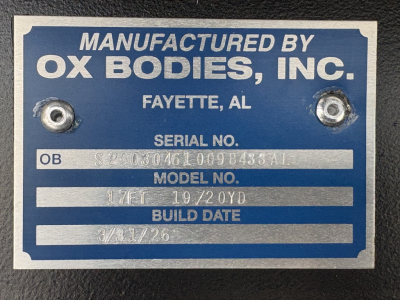 Manufacturer plate showing model and build data: ‘Manufactured by OX Bodies, Inc.’, Fayette, AL with serial number, model no, build date 3/31/26; two screw holes.