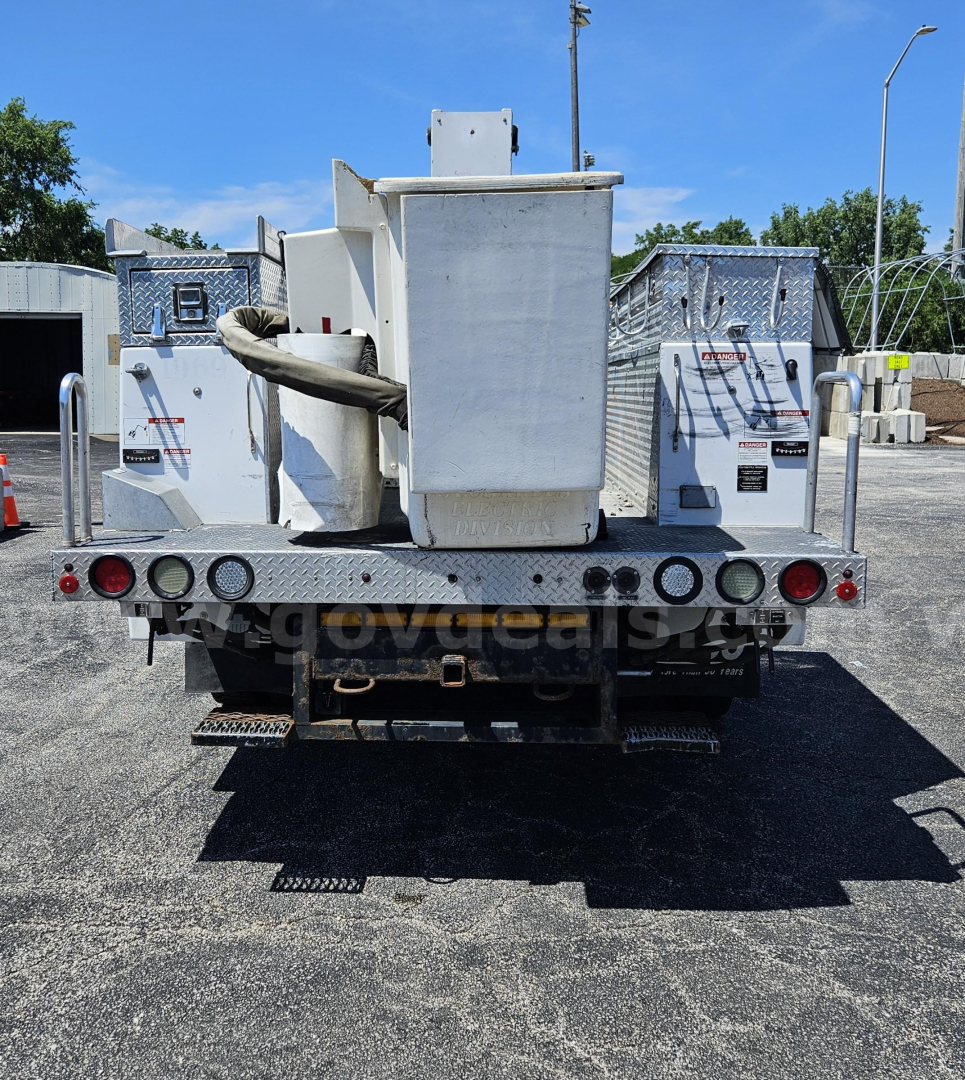 Rear view of a 2009 Ford F-550 utility/service truck with a large central equipment box and dual aluminum bodies, light bulbs and hookups visible on tailgate area.