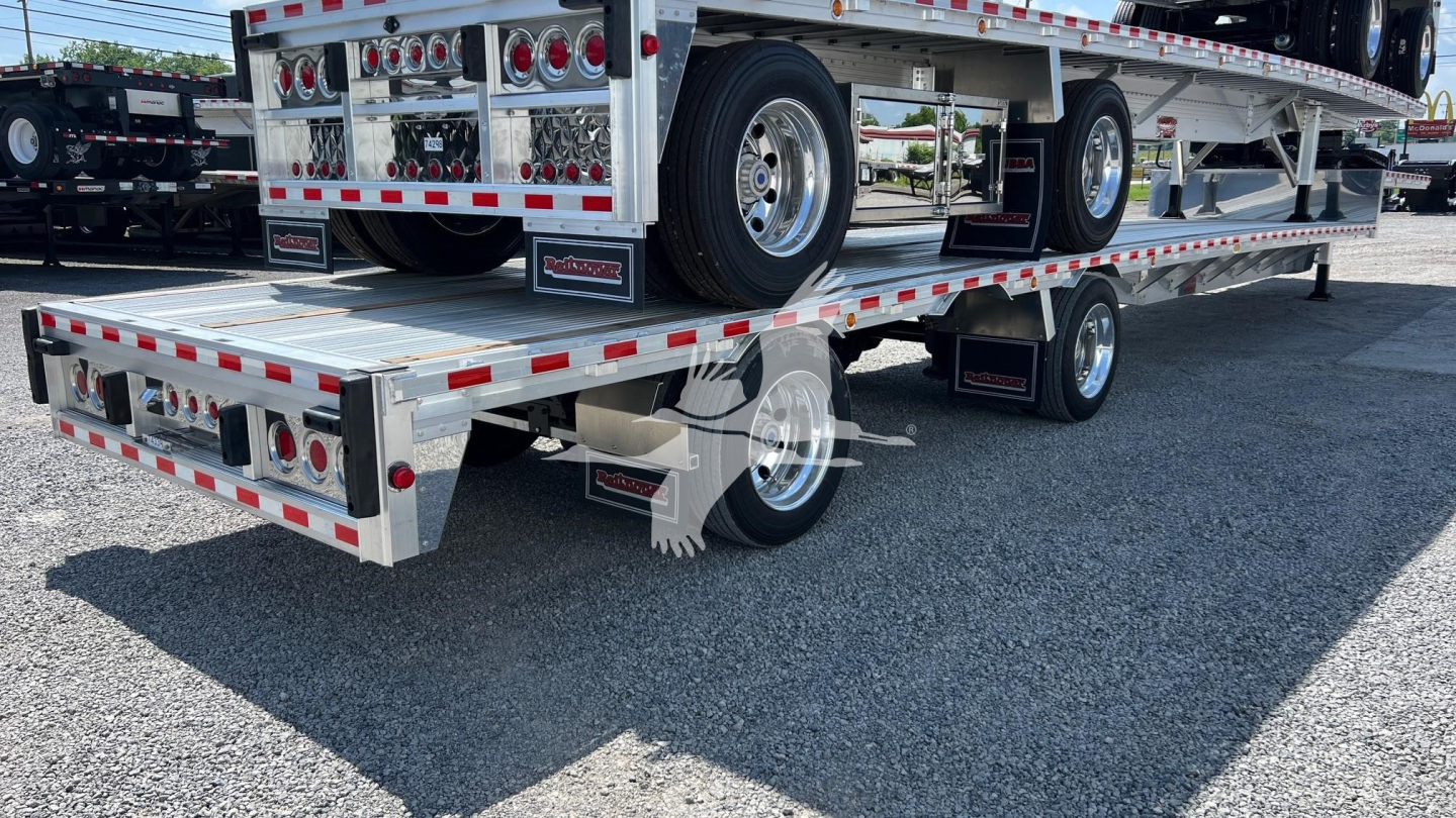 Trailer showing lower deck of a dropdeck trailer with chrome wheels and red/white reflective tape; visible are taillights, rear bumper, and a spare tire mounted under the upper deck.