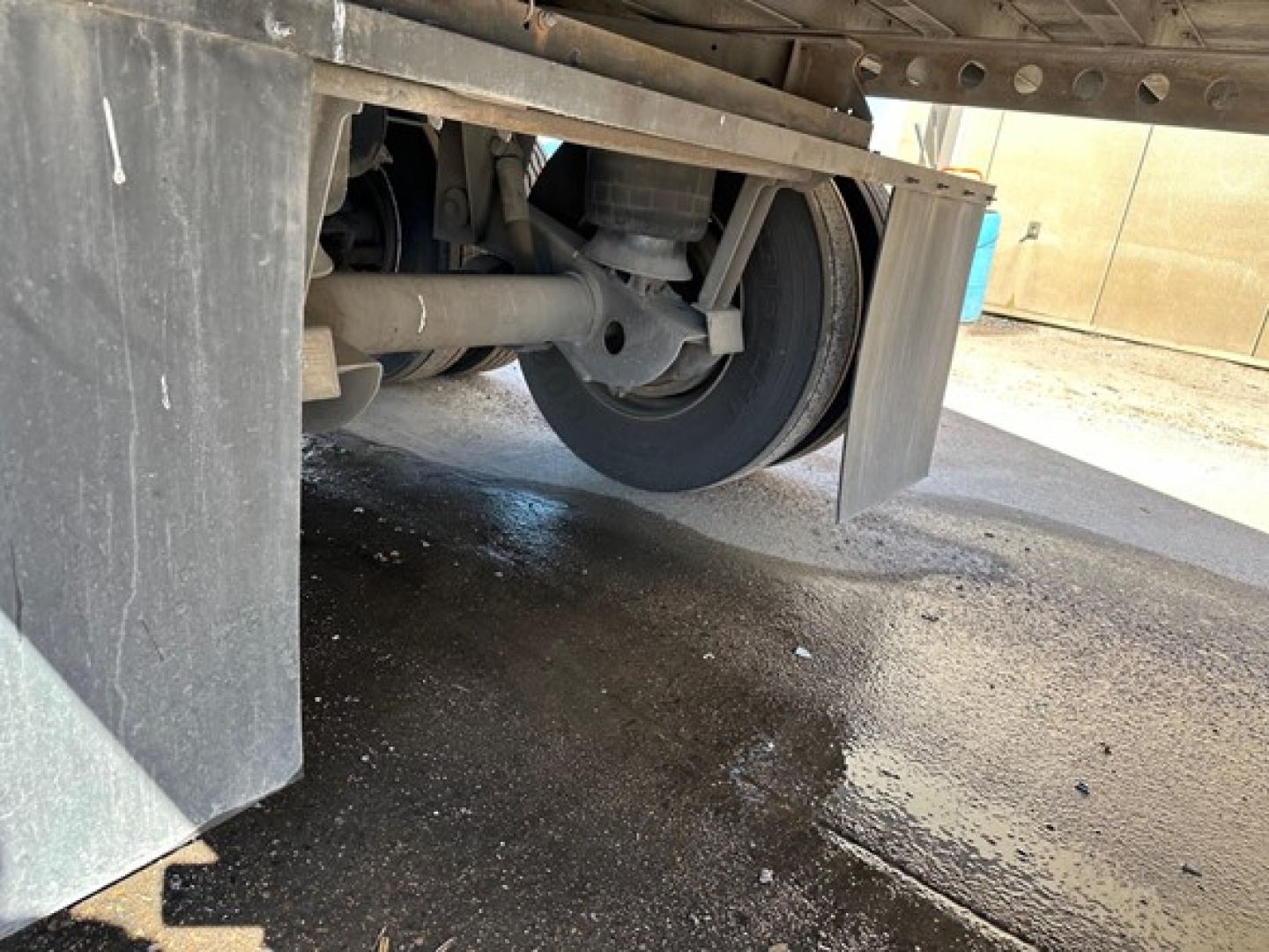 Trailer axle area showing rear suspension and wheel with mudflap under the 2015 Hyundai air ride dry van.